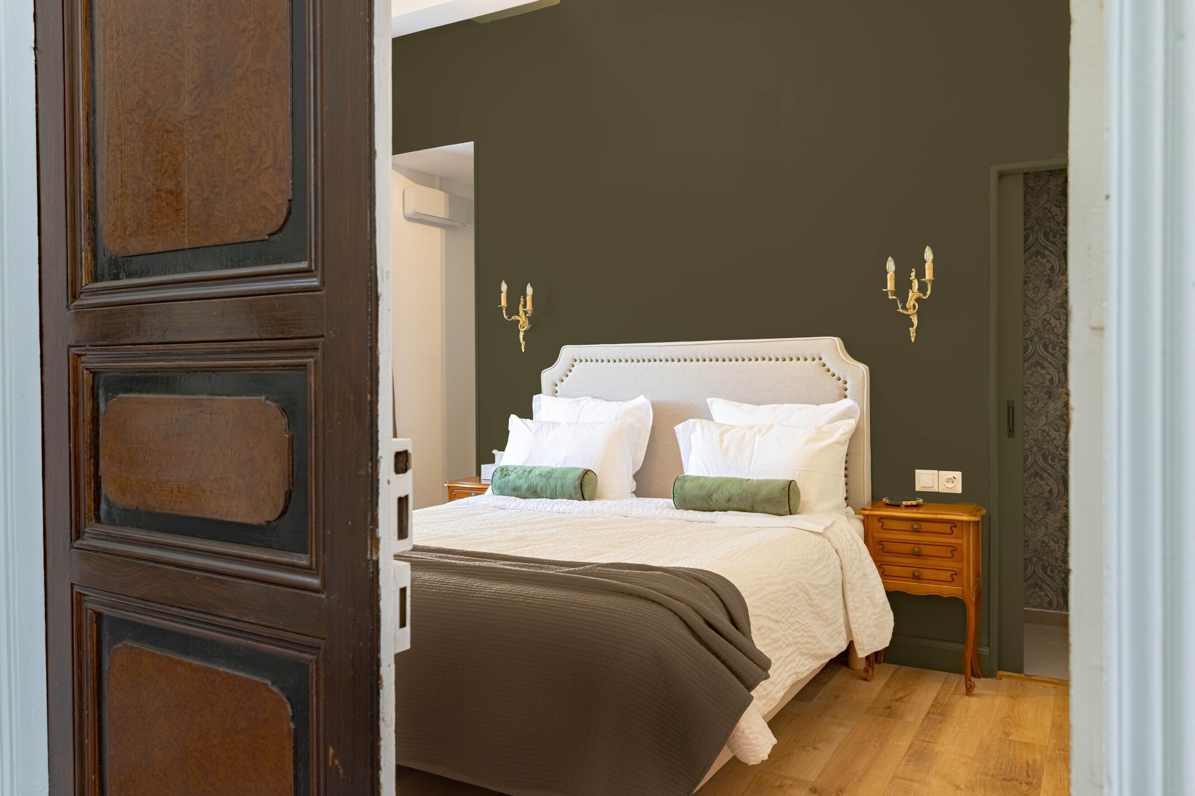 Ein Schlafzimmer mit einem großen Bett, einem Holznachttisch und einer wandmontierten Leuchte.