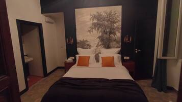 Een hotelkamer met een groot bed, een nachtkastje, een wandlamp en een deur.