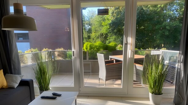 A modern living room with a sofa, a coffee table, and a balcony with a table and chairs.