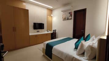 A hotel room with a bed, a desk, a television, and a wardrobe.