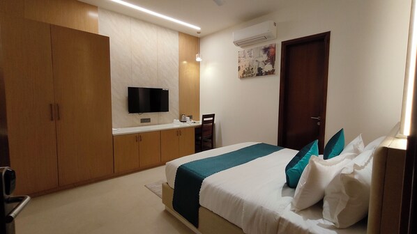 Una habitación de hotel con cama, escritorio, televisión y armario.