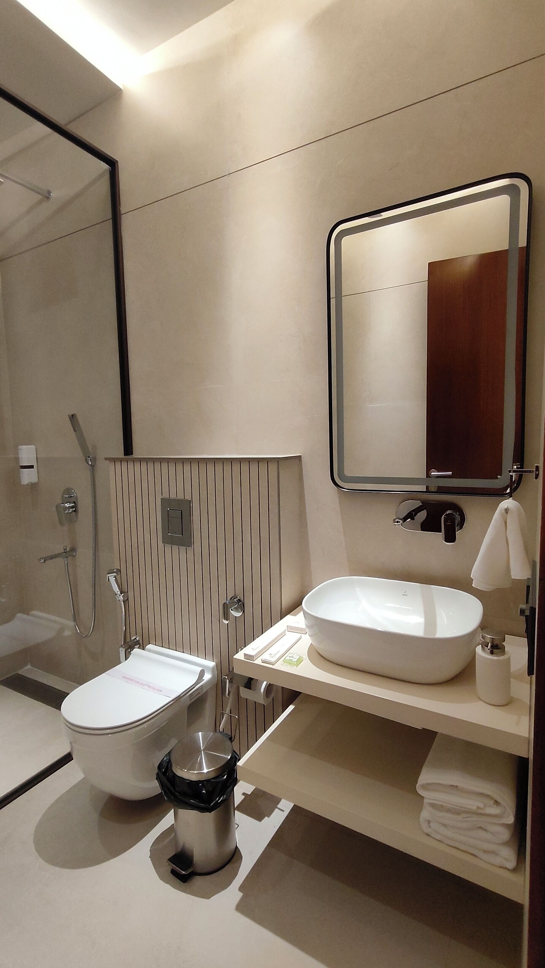 A modern bathroom with a toilet, bidet, sink, and a large mirror.