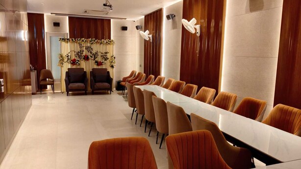 A conference room with a long table and multiple chairs, a projector, and a decorative floral arrangement. - Radiance Hotel (Sirsa)