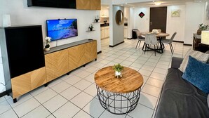 Ett modernt vardagsrum med TV, soffa, soffbord och en takfläkt.