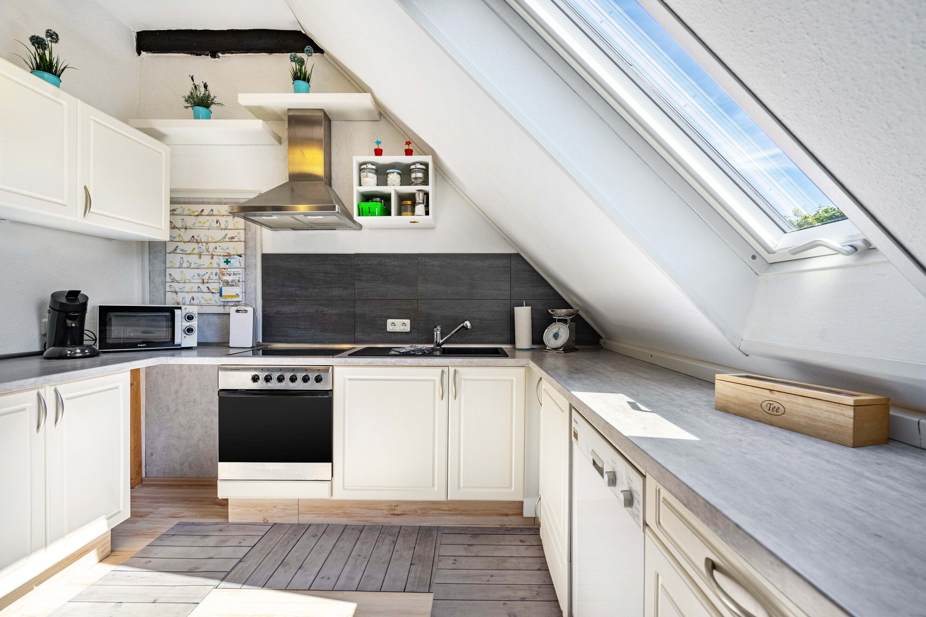 Eine moderne Küche mit Oberlichter, eingebauten Geräten und Holzboden.
