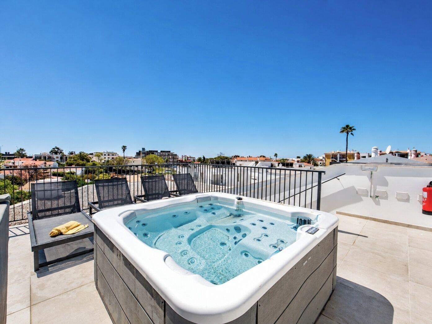 A rooftop terrace with a hot tub, lounge chairs, and a clear view of the cityscape.
