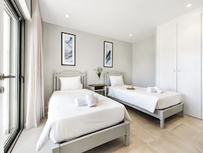 A hotel room with two beds, a wardrobe, and artwork on the walls.