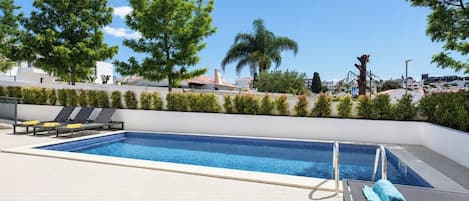 A rooftop pool with lounge chairs and a clear view of the surrounding buildings.