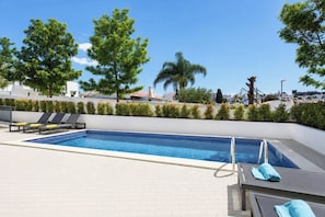 A rooftop pool with lounge chairs and a clear view of the surrounding buildings.