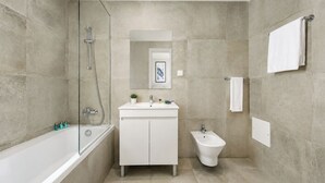 Een moderne badkamer met een badkuip, wastafel, toilet en douche.