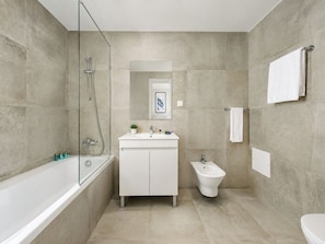 A modern bathroom with a bathtub, a sink, a bidet, and a shower.
