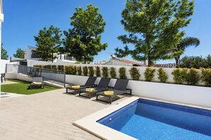 Ein moderner Poolbereich im Freien mit Liegestühlen und türkisfarbenem Wasser.