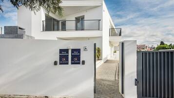 Een modern, twee verdiepingen tellend gebouw met een witte gevel, een hekkenpoort en borden met 'Villa Margarida' en 'Villa Magnolia', met branding van 'DK STAYS'.
