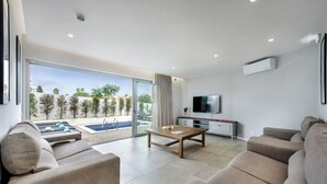 Ein modernes Wohnzimmer mit Blick auf einen Pool, einem Flachbildfernseher und einem Sofa.