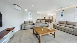 Ein modernes Wohnzimmer mit Sofas, einem Couchtisch und einem Fernseher.