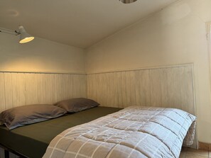 A single bed with a checkered duvet, a bedside lamp, and a wooden panel wall. - Retreat Zerbo Viesci (Chiusavecchia)
