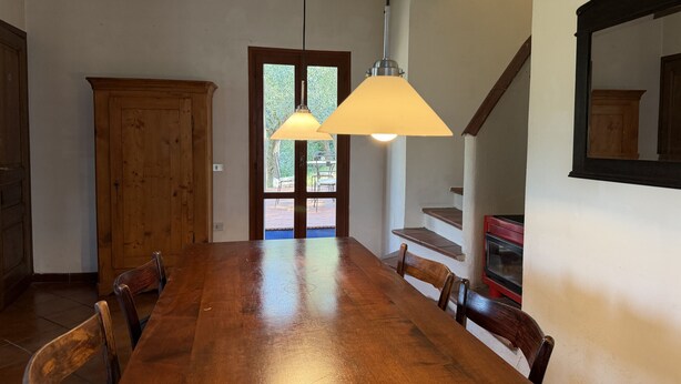 Un coin repas avec une table et des chaises en bois, un buffet en bois et un escalier sur lequel se trouve un appareil électroménager rouge.
