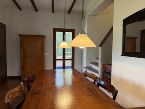 Un comedor con mesa y sillas de madera, un armario de madera y una escalera con un electrodoméstico rojo.