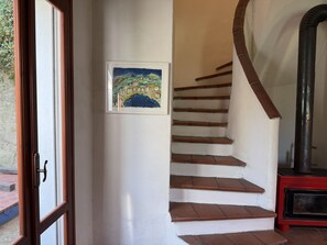 Eine Treppe mit Holzboden, ein roter Heizkörper, ein gerahmtes Bild an der Wand und eine Tür, die nach draußen führt.
