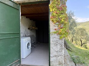 Un área de lavandería con lavadora, tendedero y una puerta que da a un espacio exterior cubierto.