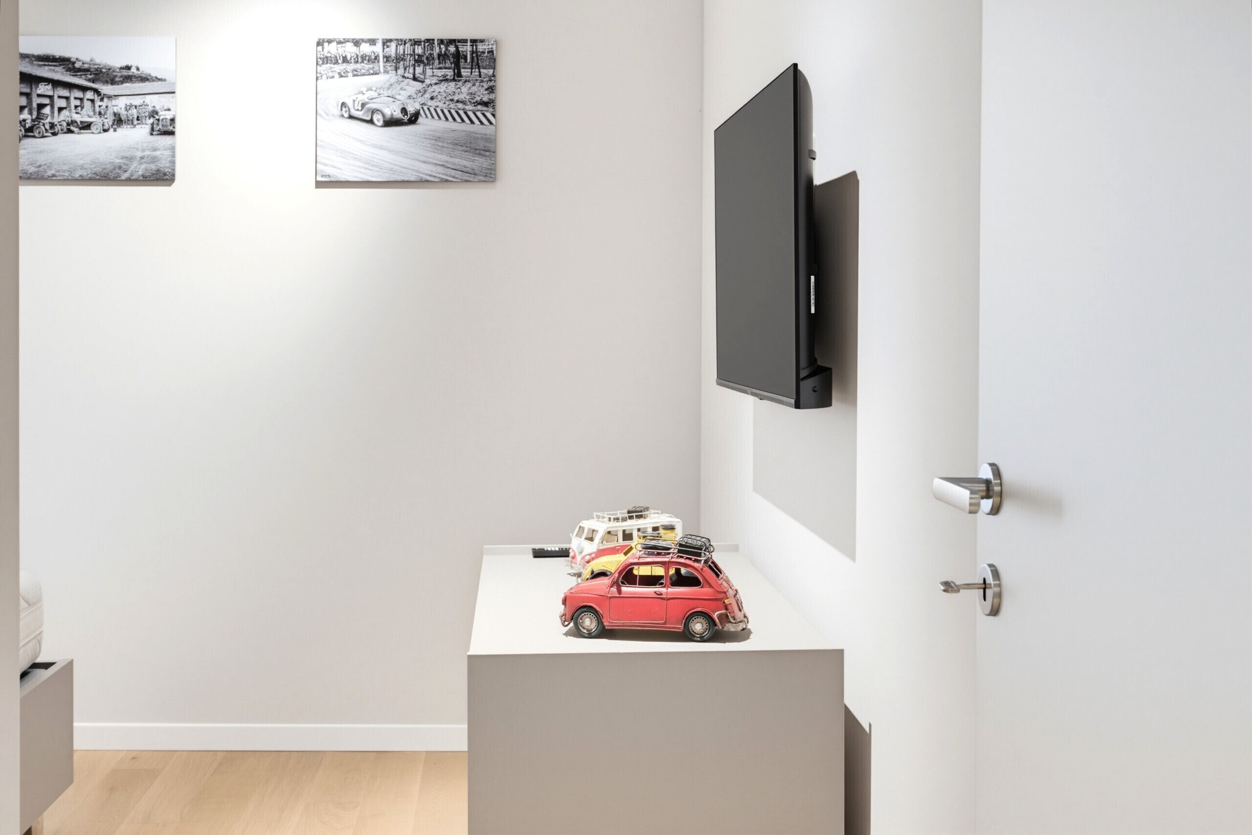 A modern room with a flat-screen TV mounted on the wall, a whiteboard, and a small table with toy cars.