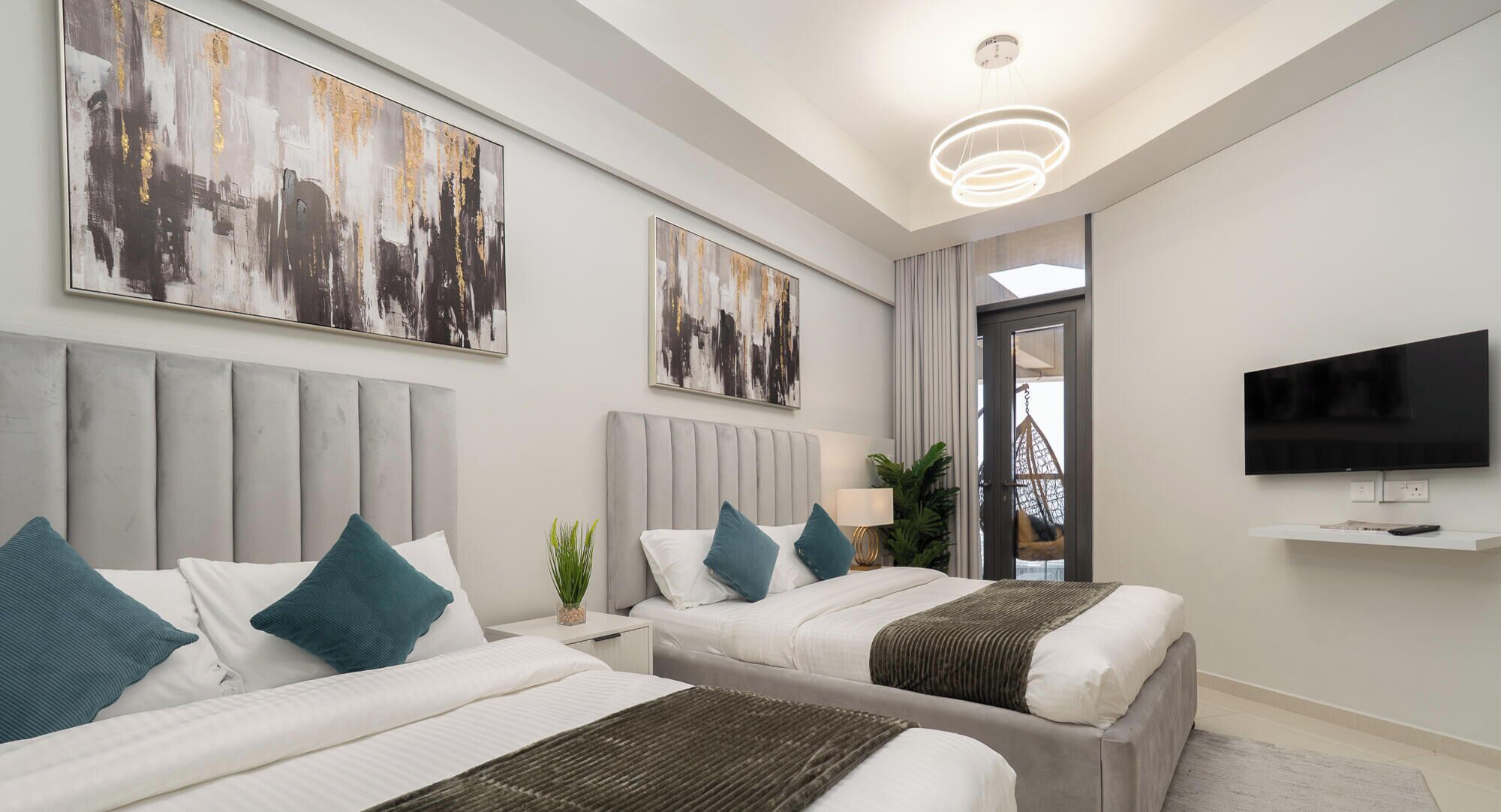 A modern hotel room with two beds, a flat-screen TV, and artwork on the walls.