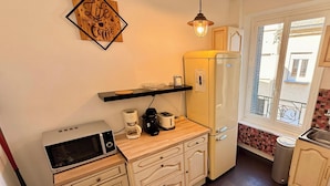Eine kleine Küche mit Mikrowelle, Kaffeemaschine, Toaster und Kühlschrank.