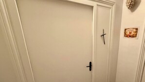 Eine weiße, geschlossene Tür mit schwarzem Türgriff und Schlüsselloch.