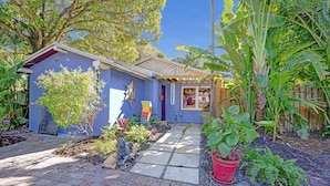 A house with a blue exterior, a paved pathway, and various plants.