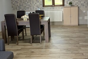 Un coin repas avec une table et des chaises en bois, un radiateur et un meuble.
