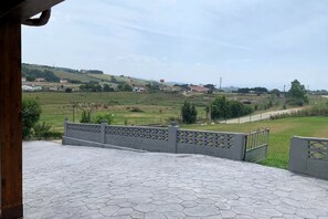 A paved patio area with a view of a rural landscape, including fields and distant buildings. - C19A02 Cozy Accommodations in Miengo (Miengo)