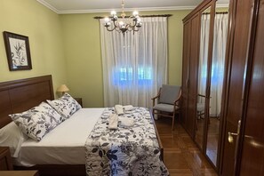 Une chambre d’hôtel avec un lit, une chaise, une armoire et un lustre.