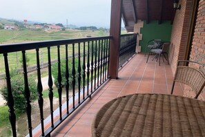 A balcony with a view of a rural landscape, a wicker chair, and a table. - C19A02 Cozy Accommodations in Miengo (Miengo)