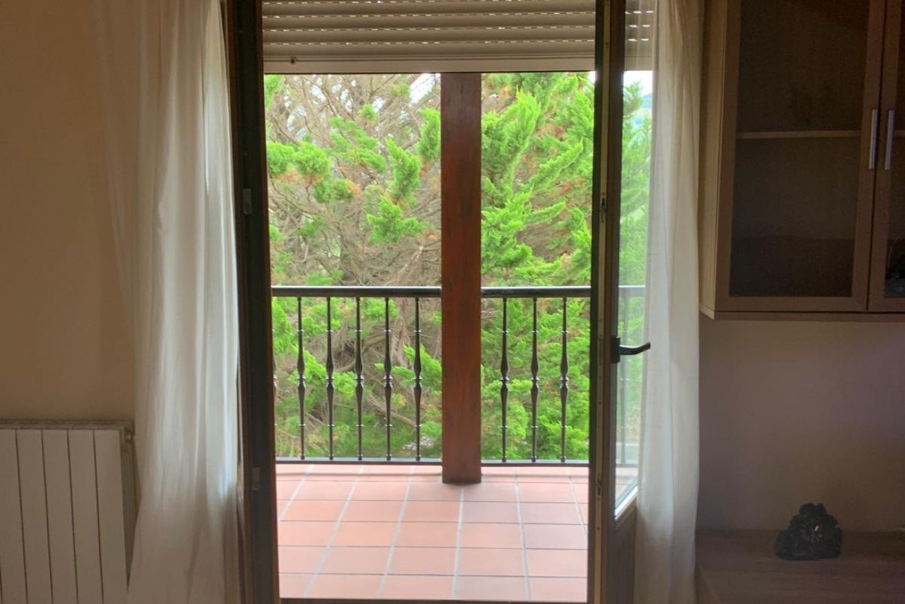 Une pièce dotée d’une porte-fenêtre donnant sur un balcon carrelé, protégé par une rambarde en métal.