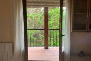 Une pièce dotée d’une porte-fenêtre donnant sur un balcon carrelé, protégé par une rambarde en métal.