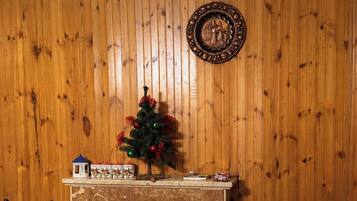 A fireplace with a Christmas tree, a mantel with decorative items, and a wooden wall.