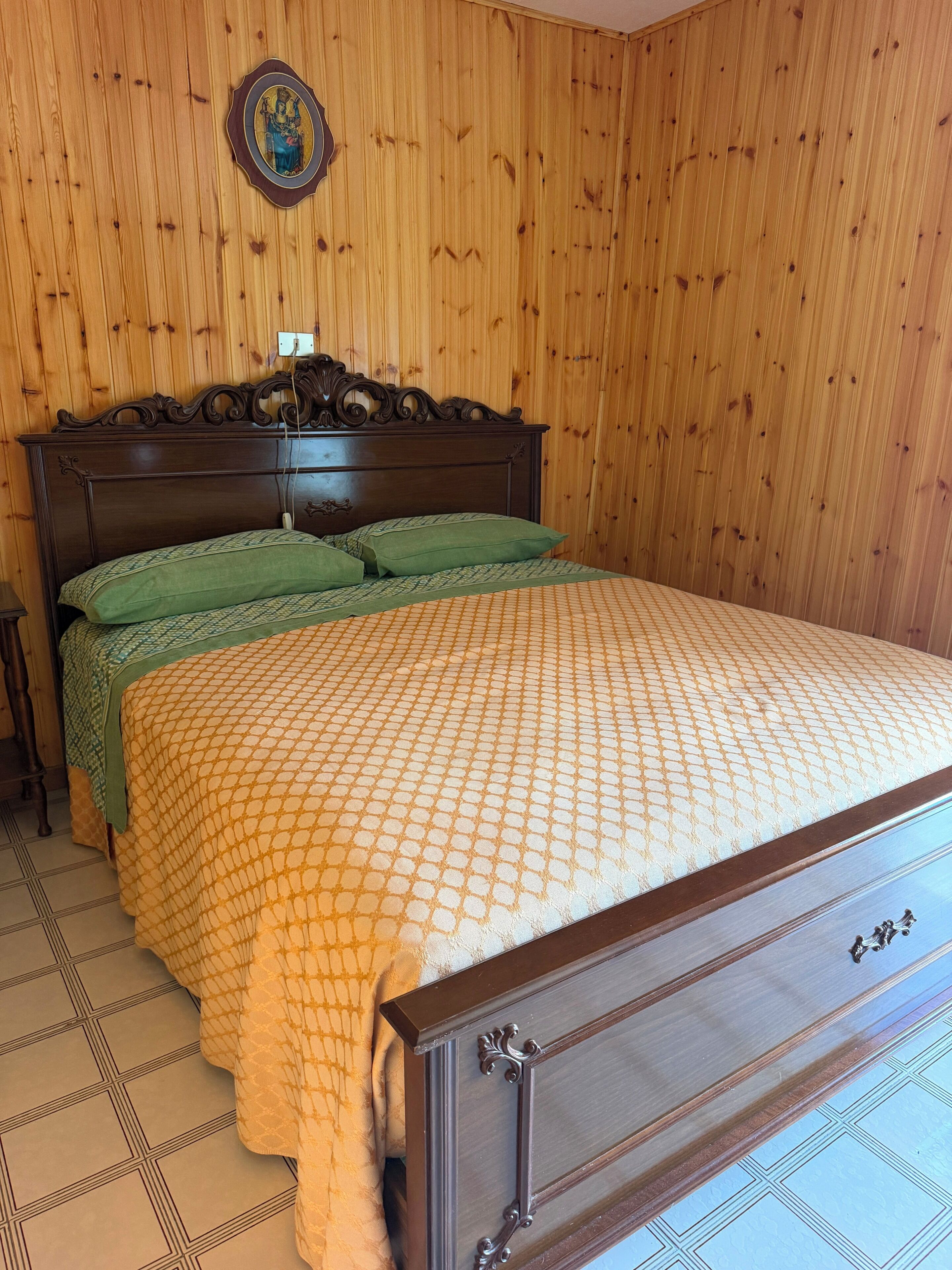 Una habitación con paneles de madera y una cama con colcha y almohadas a juego.