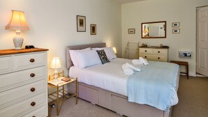 Een slaapkamer met een bed, nachtkastjes, een kaptafel, een spiegel en foto's aan de muur.