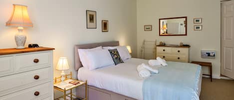 Een slaapkamer met een bed, nachtkastjes, een kaptafel, een spiegel en foto's aan de muur.