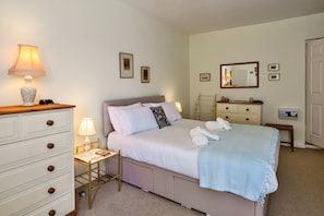 Ein Schlafzimmer mit Bett, Nachttischen, einem Schminktisch, einem Spiegel und Bildern an der Wand.