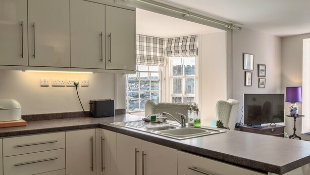 Een moderne keuken met een inbouwoven, een spoelbak en een raam met geruit gordijnen.