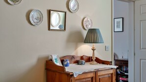 Een kamer met een houten bankje, een lamp en decoratieve borden aan de muur.