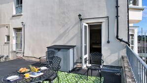 Een balkon met een eettafel, terrasstoelen en een kleine opbergruimte.