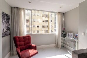 A room with a large window, a red chair, a reception desk, and a wall-mounted artwork. - Copacabana River (Rio de Janeiro)