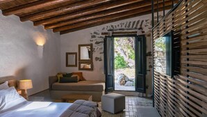 Ein Schlafzimmer mit einem Bett, einem Schlafsofa, einem kleinen Tisch, einer Lampe und einem Fenster mit Blick ins Freie.