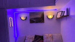 Una camera da letto con un letto, cuscini, un quadro, applique e illuminazione a LED.
