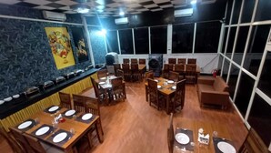A restaurant with multiple dining tables, chairs, and a buffet counter. - Hotel President Crown (Greater Noida)