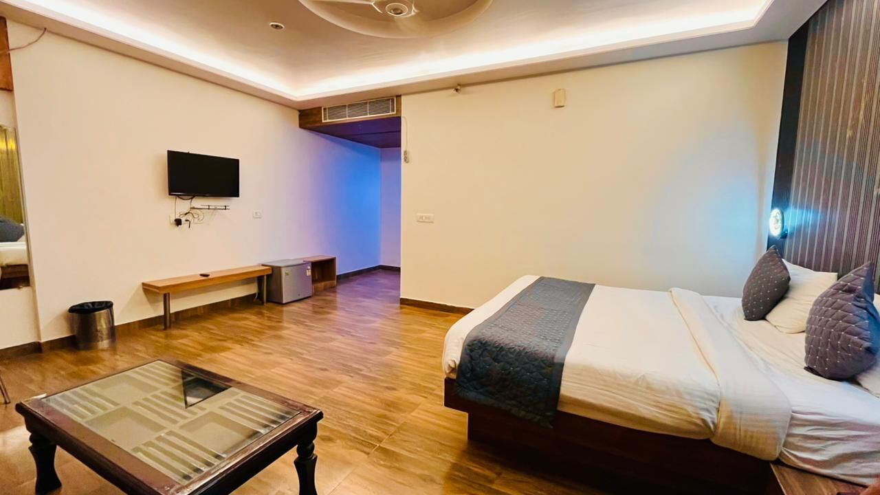 Une chambre d’hôtel moderne équipée d’un lit, d’une télévision, d’un banc et d’une petite table.