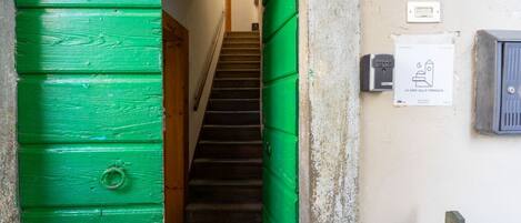 A staircase leading to a landing with a green door and a sign indicating a house on the terrace.
