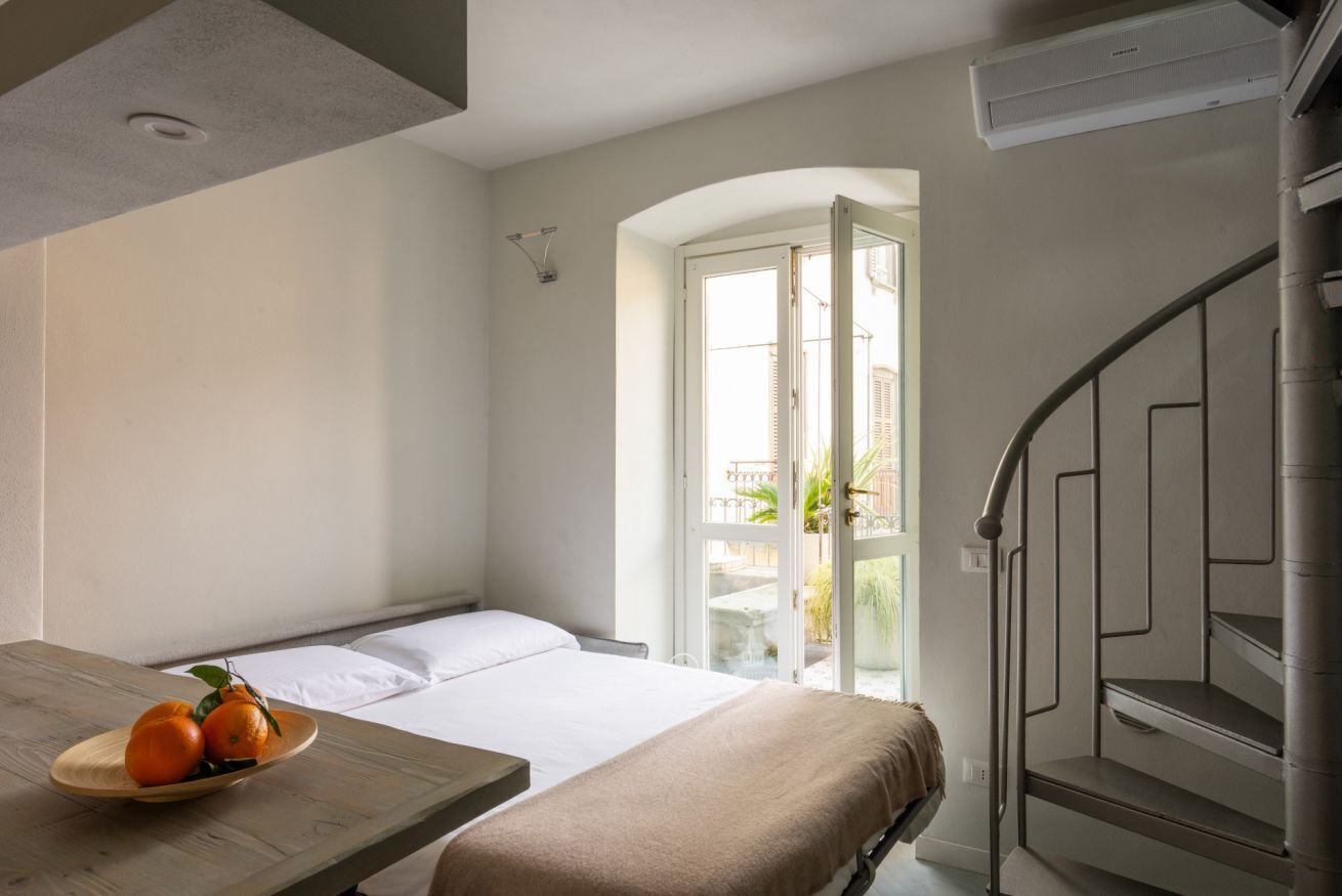 Ein Hotelzimmer mit einem Bett, einem Tisch mit Obst, einer Treppe und Blick ins Freie.
